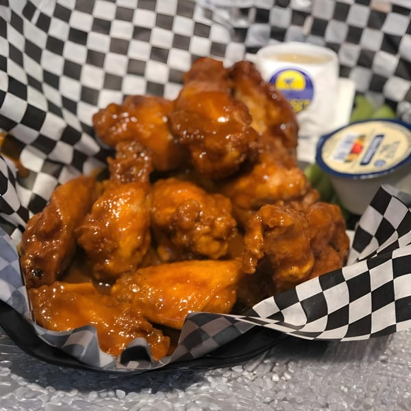 Jack's Pizza's buffalo wings in a checkered paper-lined basket with dipping sauces.